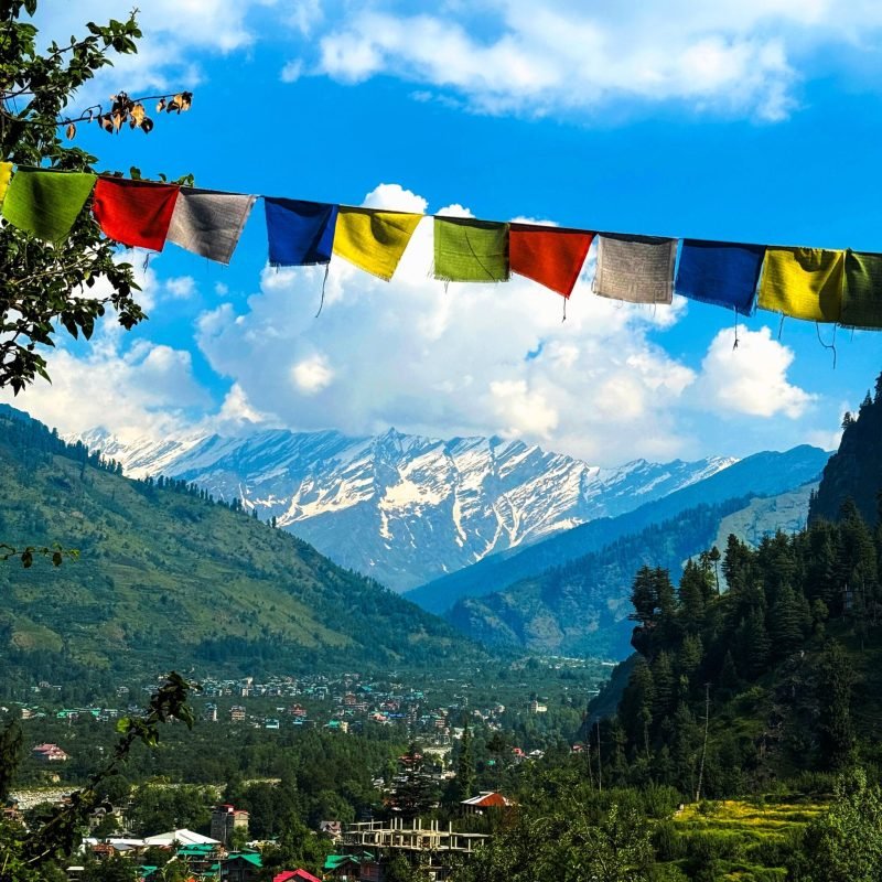Charming view of Manali village with Himalayan mountains and colorful prayer flags in summer.